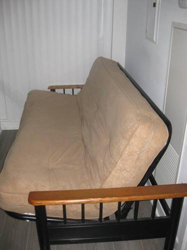 Rod iron futon with beige cushion and wooden arms