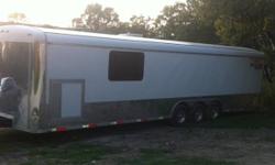 Triple axle 32 foot cargo express enclosed car trailer, checker plate floor, 3 spare tire compartments in floor, finished walls, front cupboards and cabinets, gen door, 120 and 12 volt interior lights, 2 outside pocket lights, 2 ft stainless strips on