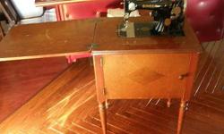GORGEOUS ANTIQUE SINGER SEWING MACHINE IN WOODEN CABINET. BEAUTIFUL DESIGN IN FRONT DOOR OF CABINET. REQUIRES SOME TLC.