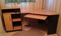 Large corner computer desk with plenty of storage space. Light coloured wood with black accents. The left section is 70" long and the right side is 40" on the two sides that fit in a corner. The left side has a raised section that is 3' high and the rest