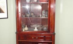 Solid wood, not laminate. 6 ft. tall, 35 inches wide at front, 15 inches deep to corner.
Glass doors on upper portion, solid doors below. One shallow pull-out drawer in middle.
Mahogany stain?