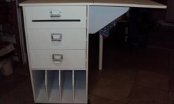 SERIOUS BUYERS ONLY PLEASE! Craft table with 3 drawers, top drawer includes ribbon dowel. Slots on the bottom house 8.5"x11" and up to 11" (vertically) card stock. Deep slots (depth of unit). Side table flips up so you can sit at it to work. On wheels
