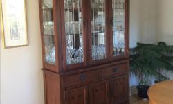 This Mission-inspired, spacious oak and cherry dining room buffet and hutch has a lighted hutch with glass sides and shelves, and a mirrored back. Buffet has 2 large drawers and a shelf in each of the 3 bottom cupboards. Buffet and hutch together measure