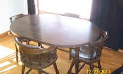 Solid English Pine, dark walnut stain, four chairs including one captain chair. Round, but oval with leaf insert (as pictured). Excellent condition.