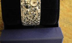 BRAND NEW in box Very unique Swarovski bangle watch covered with bubble jewels with watch face in middle. Comes with gift bag and white gloves for handling.... Would make an awesome gift.